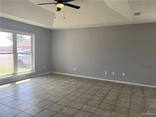 tiled empty room with a tray ceiling and ceiling fan