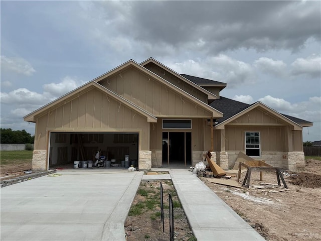 view of front of home featuring board and batten siding, driveway, stone siding, and a garage