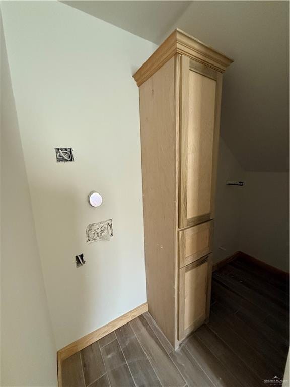 hallway featuring dark wood-style floors, baseboards, and lofted ceiling