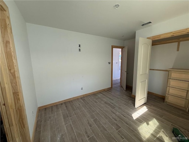 unfurnished bedroom with baseboards, visible vents, and wood tiled floor