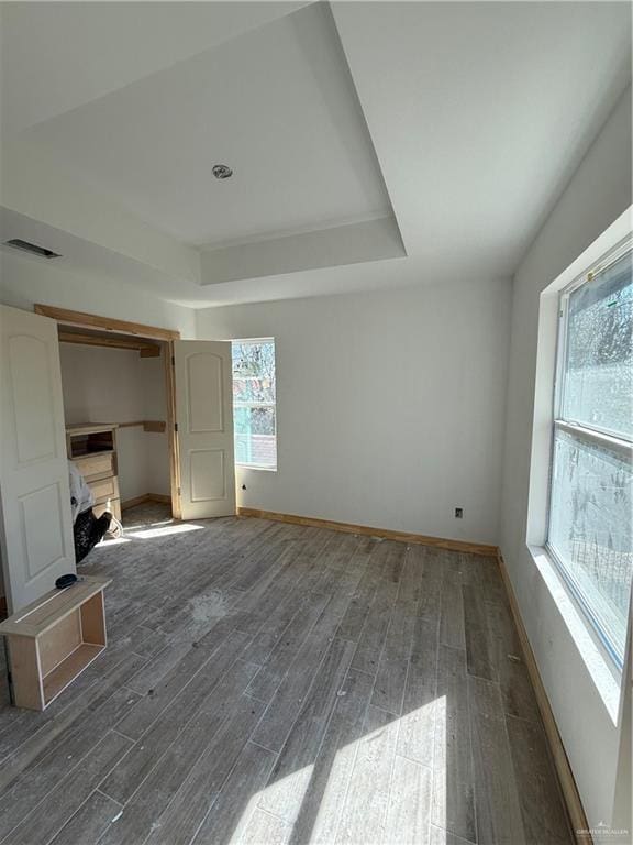 unfurnished bedroom with dark wood finished floors, baseboards, and a tray ceiling