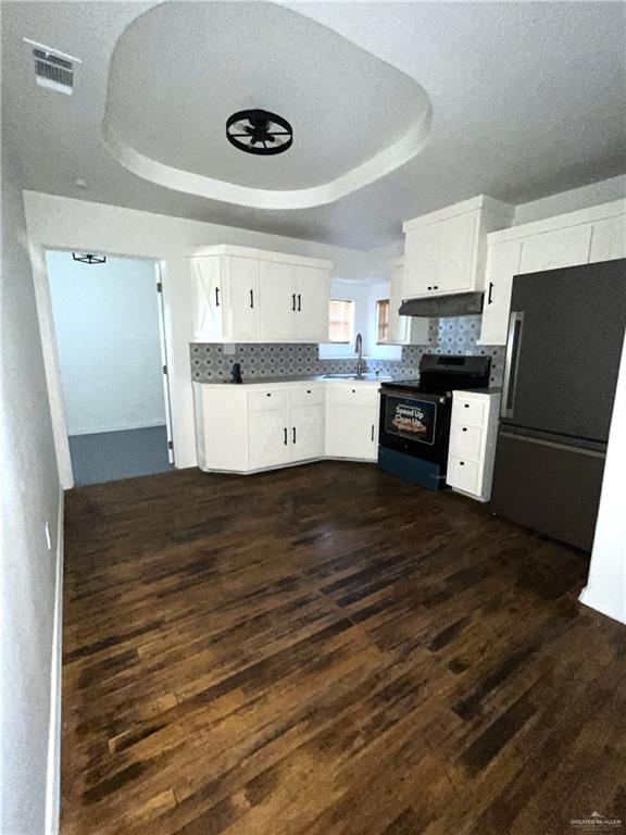 kitchen featuring a tray ceiling, tasteful backsplash, black electric range oven, and dark hardwood / wood-style floors