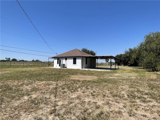 exterior space with a carport, cooling unit, and a yard