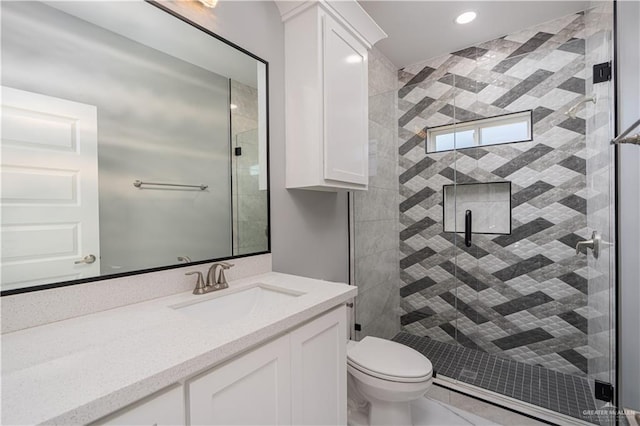 bathroom featuring toilet, vanity, and a shower with shower door