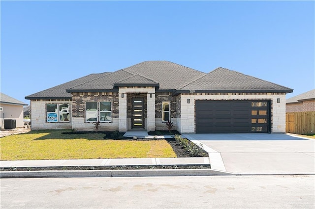 prairie-style house featuring a garage, cooling unit, and a front yard