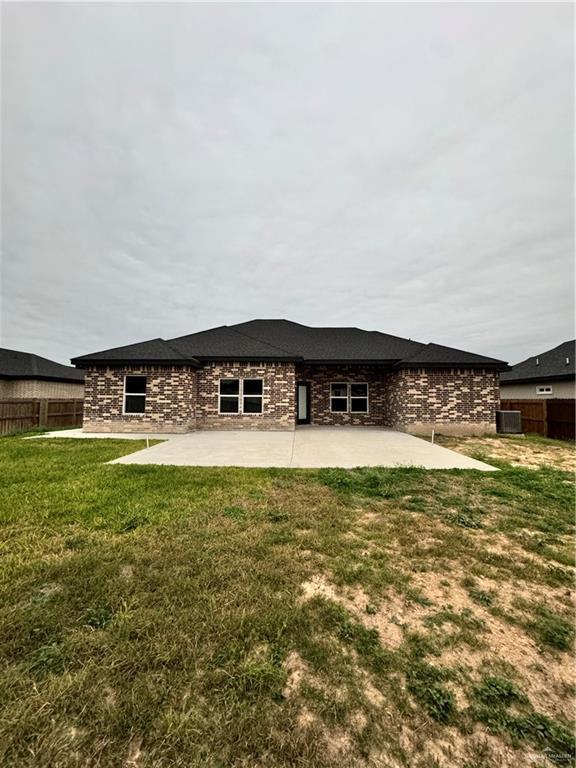 back of property with a patio, a yard, and central AC