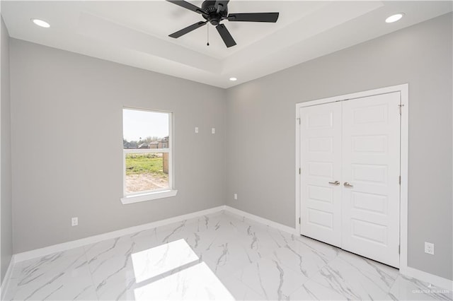 unfurnished room with a tray ceiling, a closet, and ceiling fan