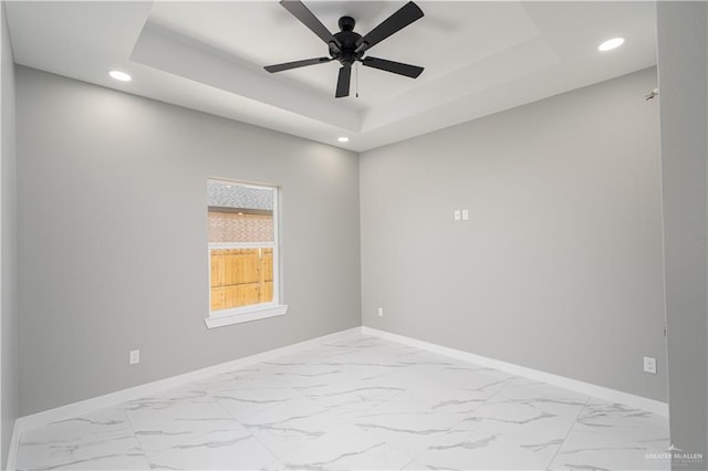 empty room featuring ceiling fan and a raised ceiling