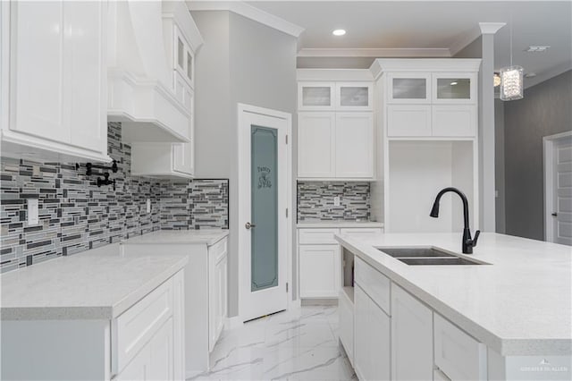 kitchen with white cabinetry, a kitchen island with sink, sink, and hanging light fixtures