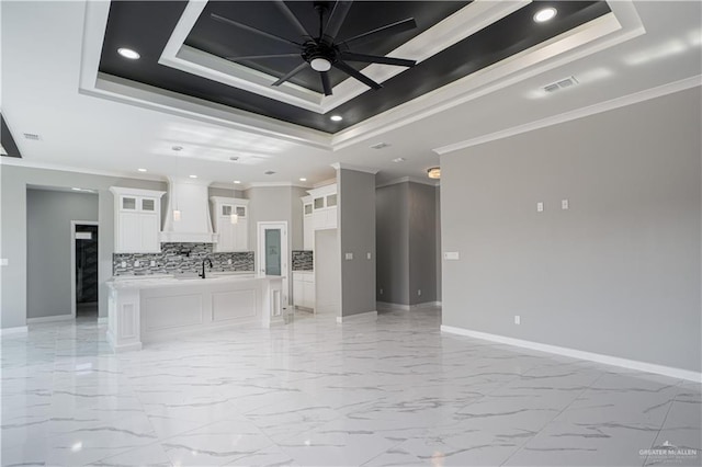 unfurnished living room featuring a tray ceiling, ornamental molding, and ceiling fan