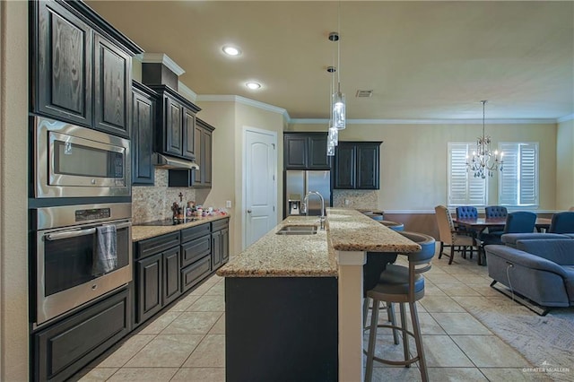 kitchen with light tile patterned flooring, a breakfast bar, appliances with stainless steel finishes, a sink, and a notable chandelier