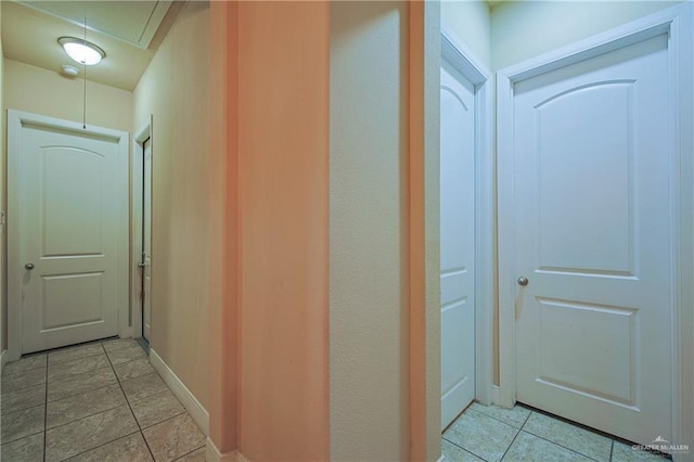 hallway with attic access, baseboards, and light tile patterned flooring