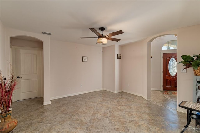 entrance foyer with visible vents, arched walkways, ceiling fan, and baseboards