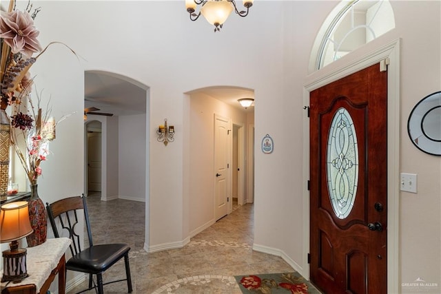 entrance foyer featuring arched walkways, ceiling fan, and baseboards