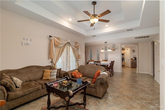 living area with arched walkways, visible vents, baseboards, a ceiling fan, and a tray ceiling