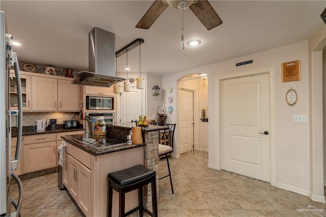 kitchen featuring a kitchen island, a breakfast bar, island exhaust hood, stainless steel appliances, and backsplash