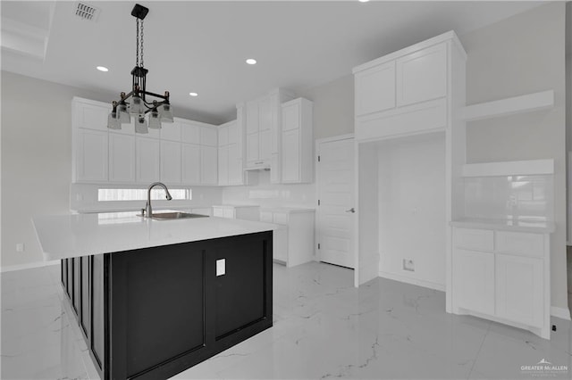 kitchen featuring white cabinetry, sink, pendant lighting, and an island with sink