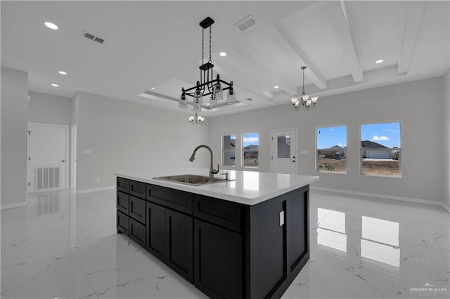 kitchen with beamed ceiling, an island with sink, sink, hanging light fixtures, and an inviting chandelier