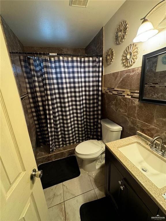 bathroom featuring curtained shower, tile patterned flooring, toilet, vanity, and tile walls