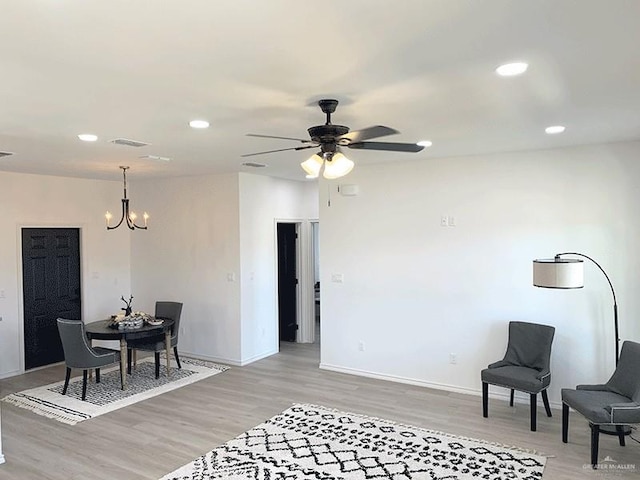 dining space featuring ceiling fan with notable chandelier and light hardwood / wood-style floors