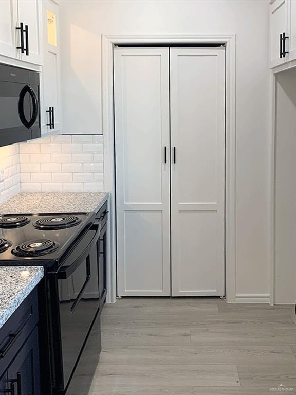 kitchen with white cabinetry, black appliances, and light stone counters