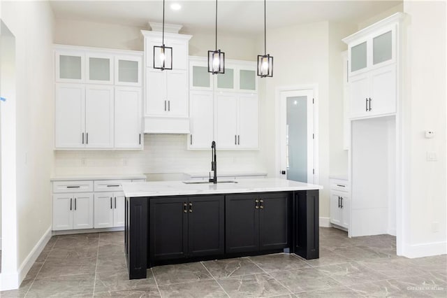 kitchen featuring decorative backsplash, white cabinetry, an island with sink, and pendant lighting