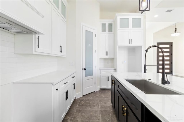 kitchen featuring decorative backsplash, sink, white cabinetry, and hanging light fixtures