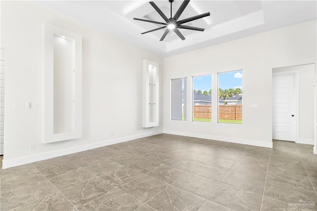 unfurnished room featuring a raised ceiling and ceiling fan