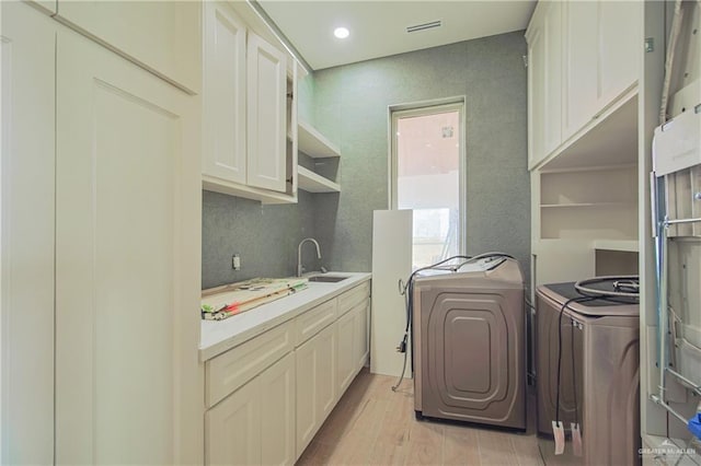 laundry room featuring recessed lighting, a sink, washer and dryer, light wood-type flooring, and cabinet space