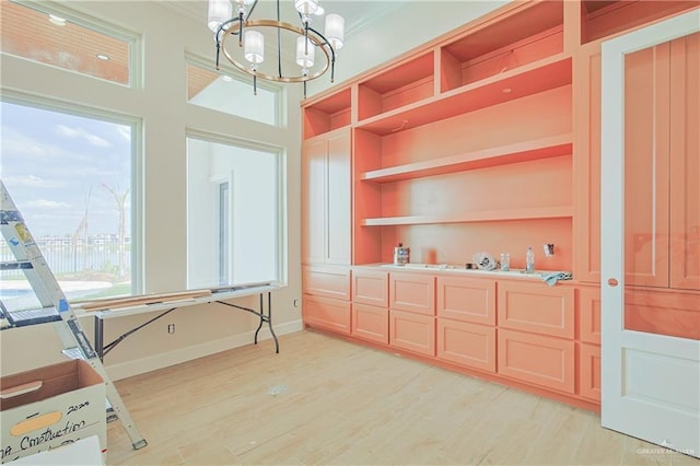 interior space with crown molding, light wood-type flooring, built in features, and an inviting chandelier