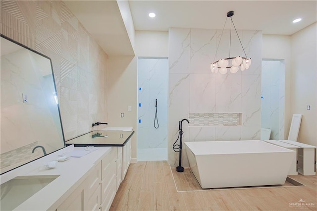 full bath with tile walls, double vanity, recessed lighting, wood finished floors, and a freestanding tub