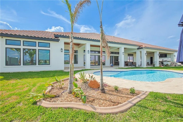 back of house featuring a patio, an outdoor pool, a tile roof, a yard, and stucco siding