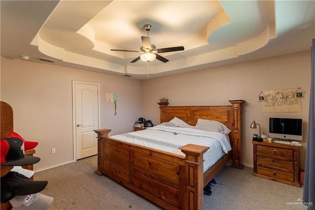 carpeted bedroom with a tray ceiling and ceiling fan