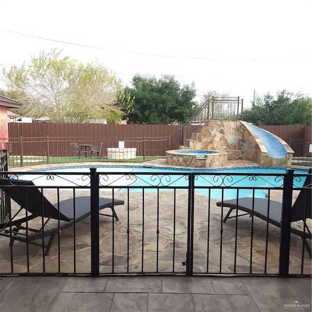 view of swimming pool with a patio area, an in ground hot tub, and a water slide