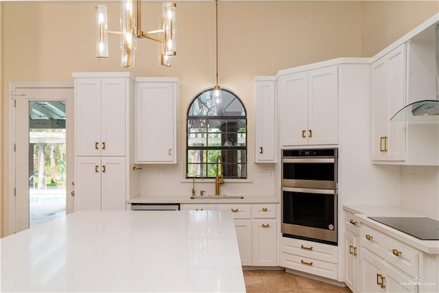 kitchen with sink, hanging light fixtures, stainless steel double oven, wall chimney range hood, and black electric stovetop