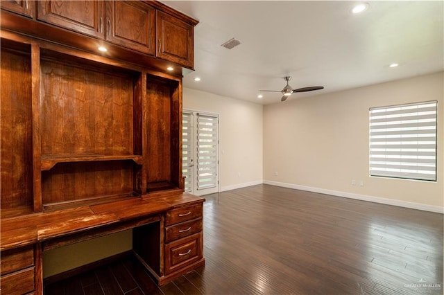 unfurnished office with ceiling fan and dark wood-type flooring