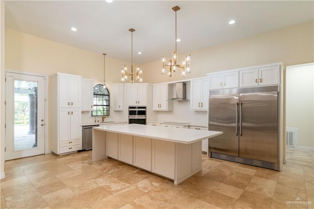 kitchen with stainless steel appliances, a kitchen island, plenty of natural light, and wall chimney range hood