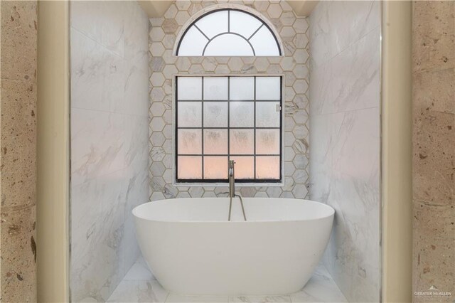 bathroom featuring a bathtub and tile walls