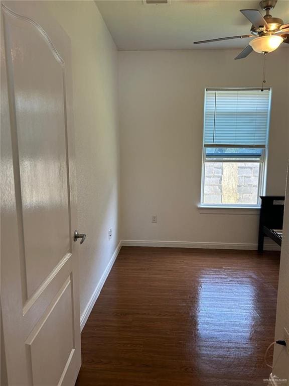 unfurnished room featuring ceiling fan and dark wood-type flooring