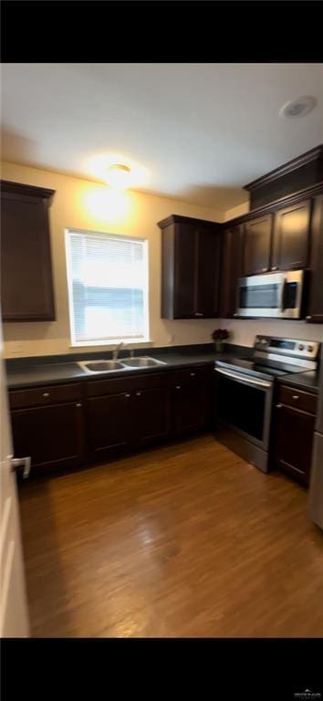 kitchen featuring sink, stainless steel appliances, dark brown cabinets, and light wood-type flooring