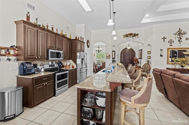 kitchen with light tile patterned flooring, visible vents, stainless steel appliances, arched walkways, and a sink