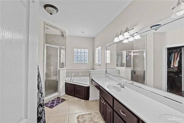 full bathroom featuring tile patterned flooring, a bath, a sink, and a stall shower