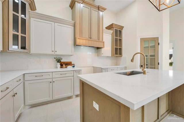 4012 Burr Dr, Edinburg, TX 78542 - kitchen with backsplash, a kitchen island with sink, glass insert cabinets, and light tile patterned floors