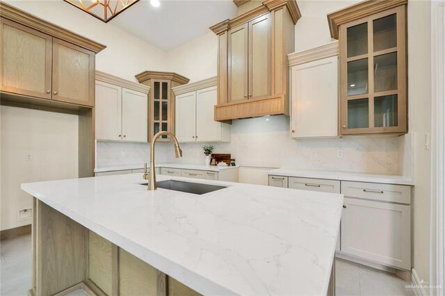 4012 Burr Dr, Edinburg, TX 78542 - kitchen with decorative backsplash, a center island with sink, light stone counters, and glass insert cabinets