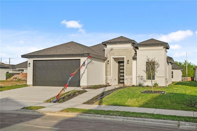 prairie-style home with driveway, a garage, roof with shingles, and a front yard