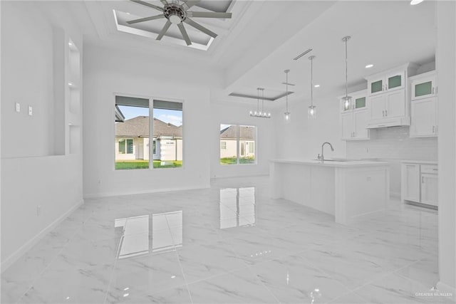 kitchen with decorative backsplash, white cabinets, marble finish floor, ceiling fan with notable chandelier, and open floor plan