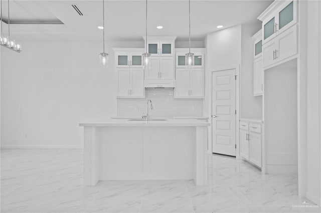 kitchen featuring light countertops, a sink, white cabinetry, tasteful backsplash, and marble finish floor
