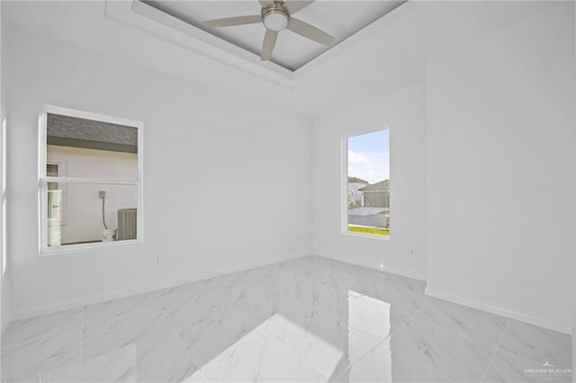 unfurnished room featuring marble finish floor, baseboards, a ceiling fan, and a raised ceiling