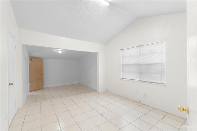 tiled spare room with vaulted ceiling and a textured ceiling