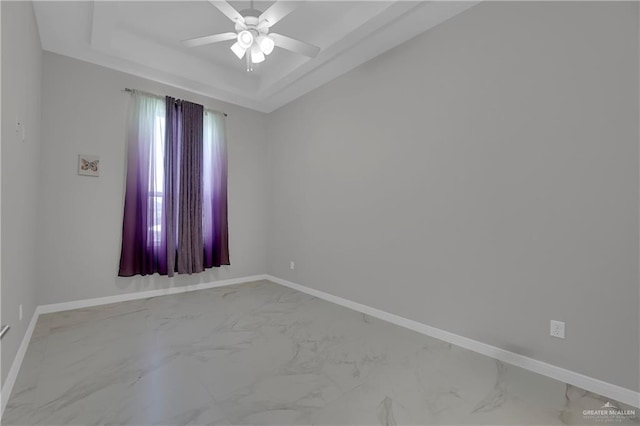 spare room with a tray ceiling and ceiling fan